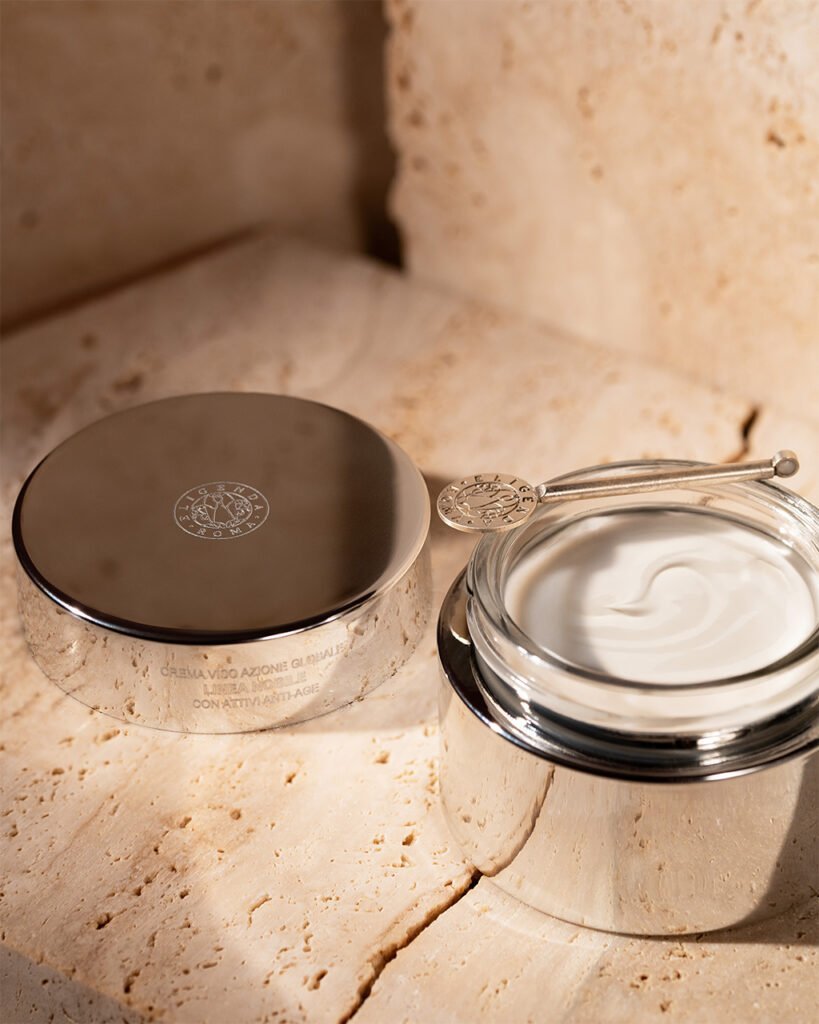 Eligenda Roma Global Action Cream, with the open jar beside its chrome lid on travertine