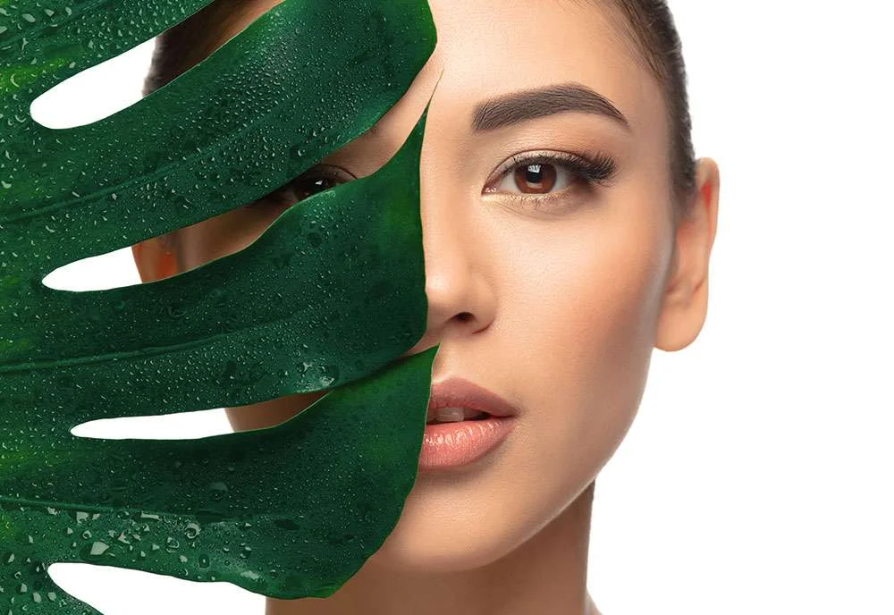 A woman’s face beside a green leaf